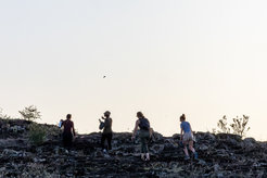Four people walking over rocky landscape